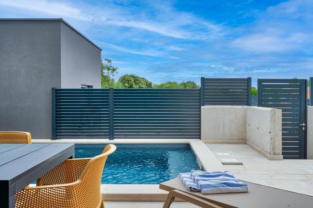 Terasa z mizo in stoli ob bazenu.