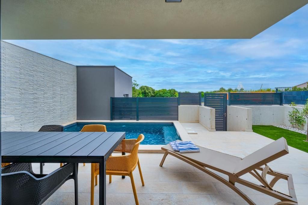 Terasa z mizo in stoli ob bazenu.