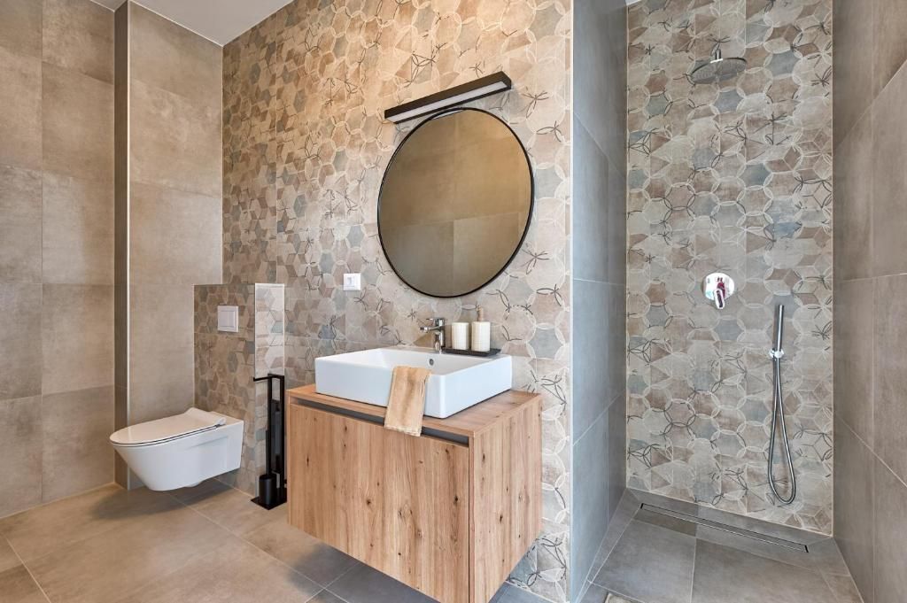 Kopalnica z umivalnikom, straniščem, ogledalom in tušem.