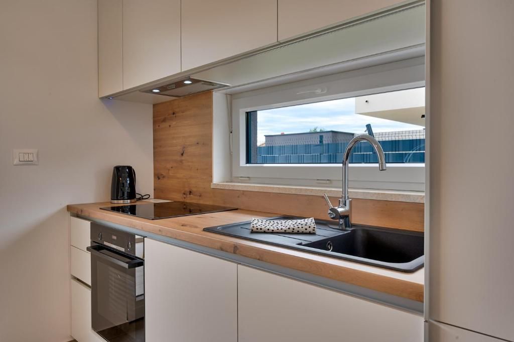 Kuhinja s pomivalnim koritom, štedilnikom, pečico in oknom.