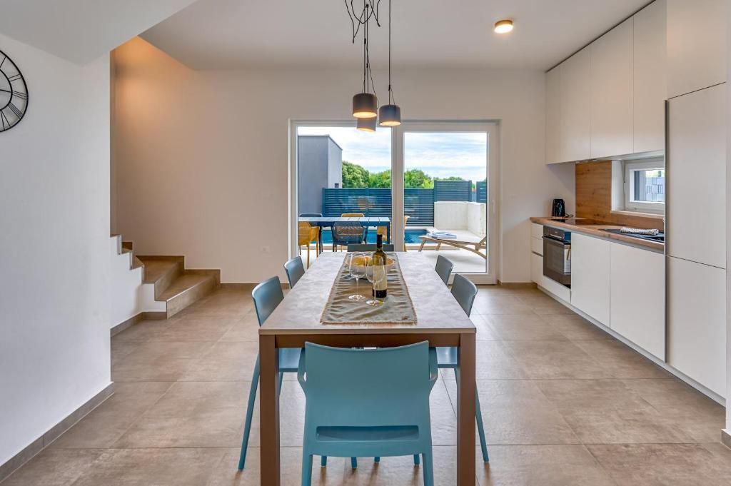 Jedilna miza in stoli v kuhinji z uro na steni.