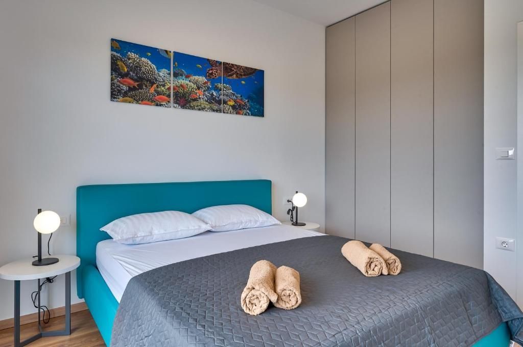 Spalnica s posteljo, dvema svetilkama, dvema brisačama in sliko na steni.