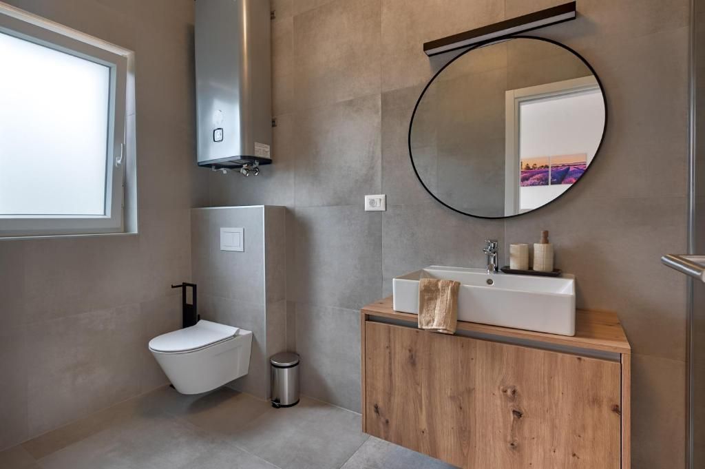 Kopalnica z WC-jem, umivalnikom in ogledalom.