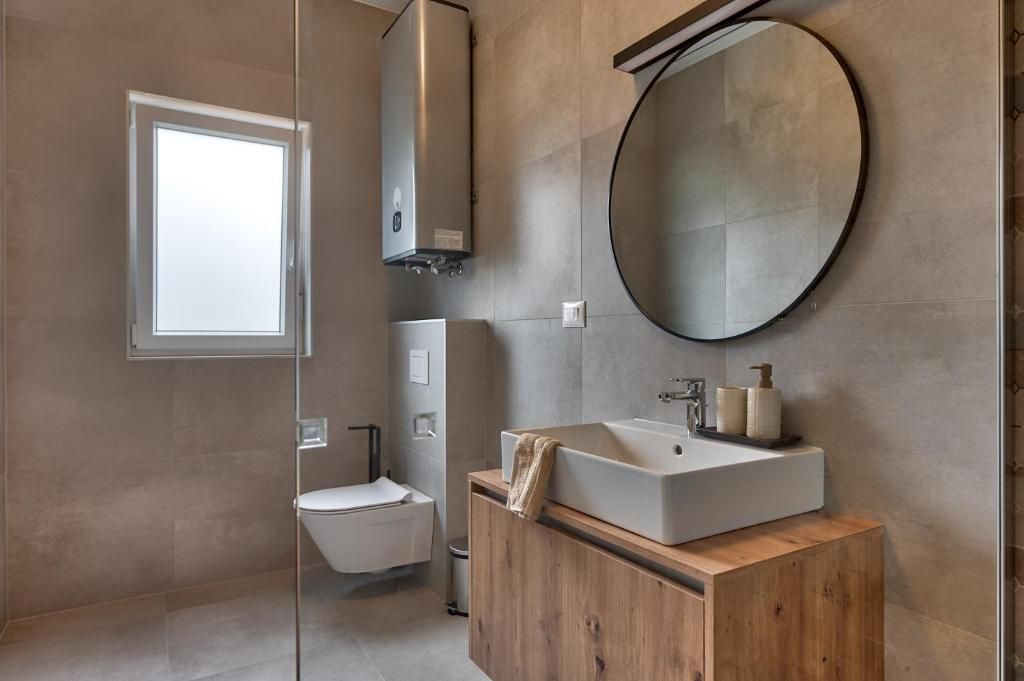 Kopalnica z umivalnikom, straniščem in ogledalom.