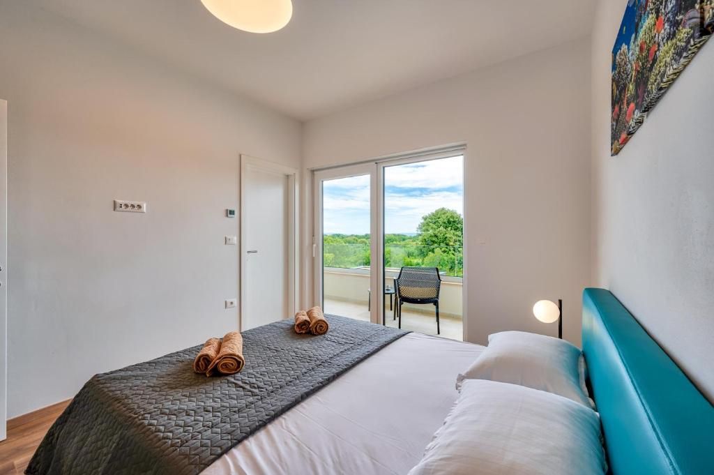 Spalnica z veliko posteljo in drsnimi steklenimi vrati, ki vodijo na balkon.