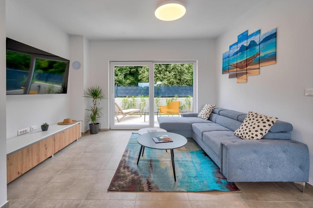 Dnevna soba s kavčem, klubsko mizico, televizijo in drsnimi steklenimi vrati.