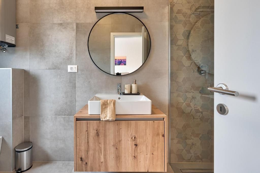 Kopalnica z umivalnikom, ogledalom in tušem.