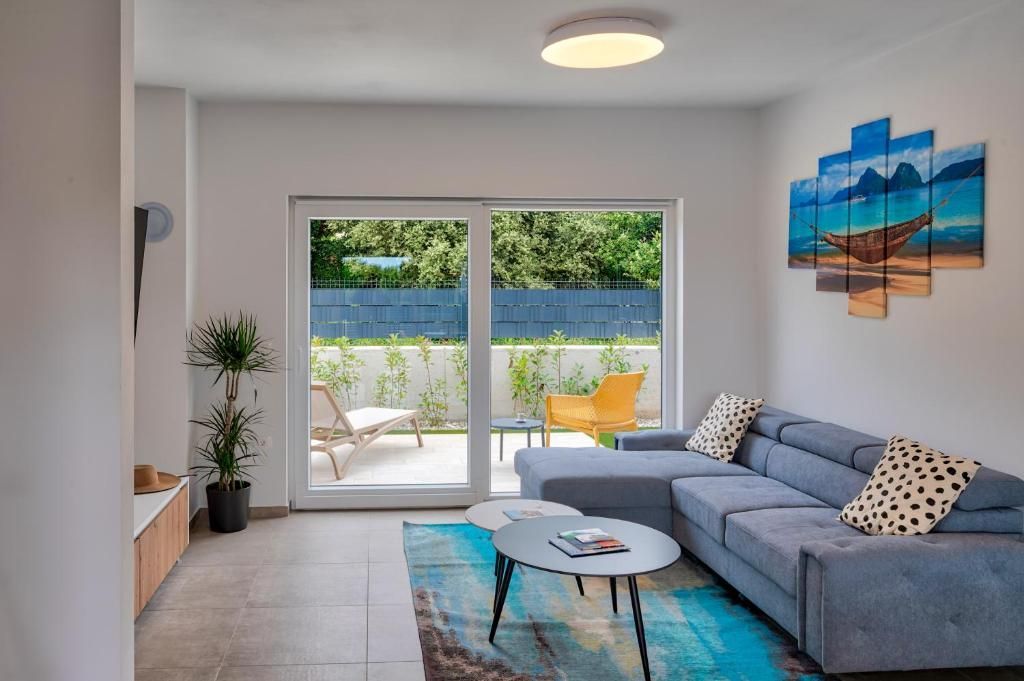 Dnevna soba s kavčem, klubsko mizico in drsnimi steklenimi vrati.