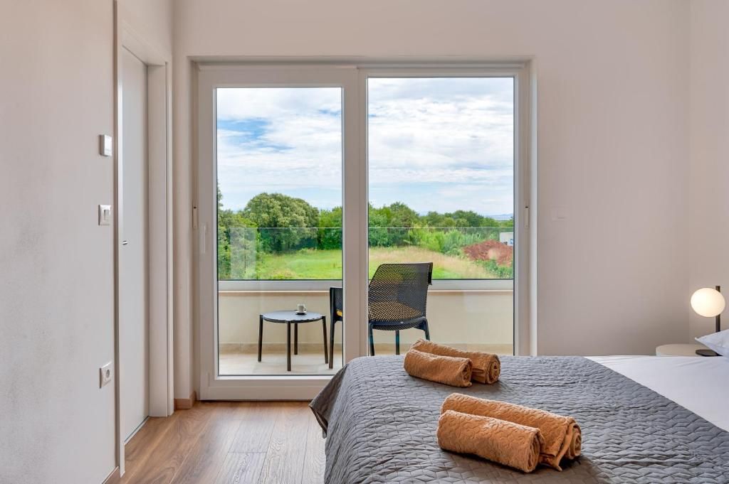 Spalnica s posteljo in balkon s pogledom na polje.