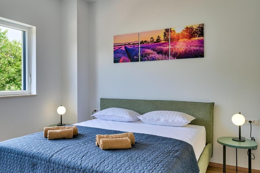 Spalnica z veliko posteljo in sliko na steni nad njo