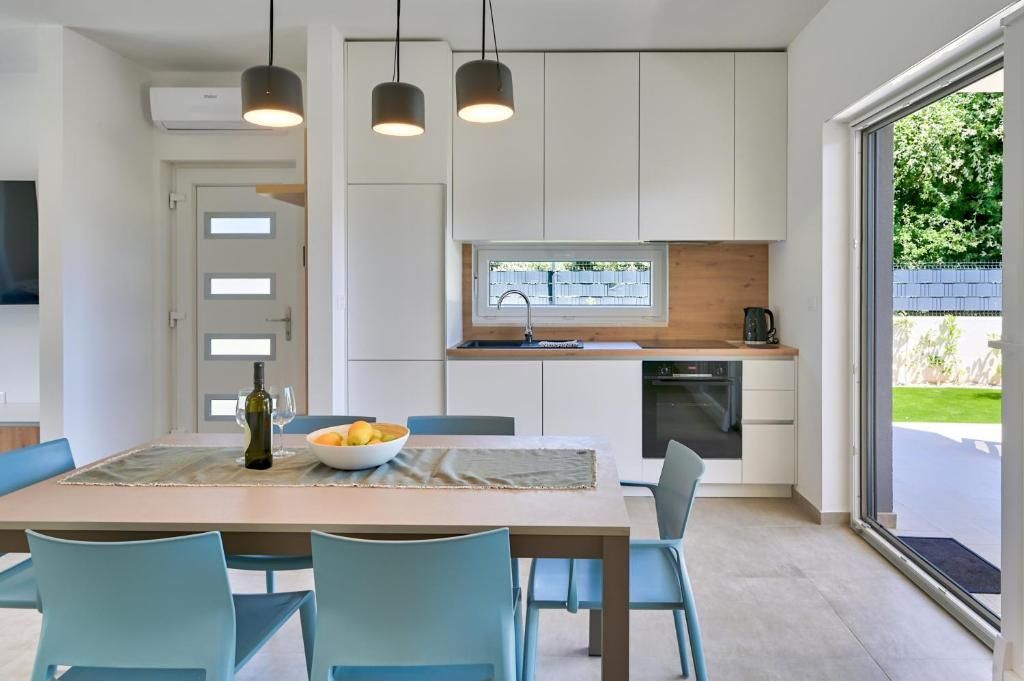 Kuhinja z mizo in stoli ter steklenico vina na mizi.