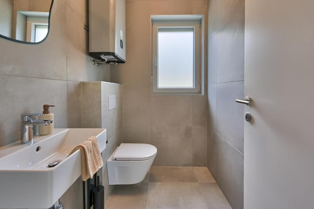 Kopalnica z umivalnikom, straniščem in oknom.