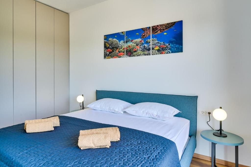 Spalnica z veliko posteljo in sliko na steni nad njo.