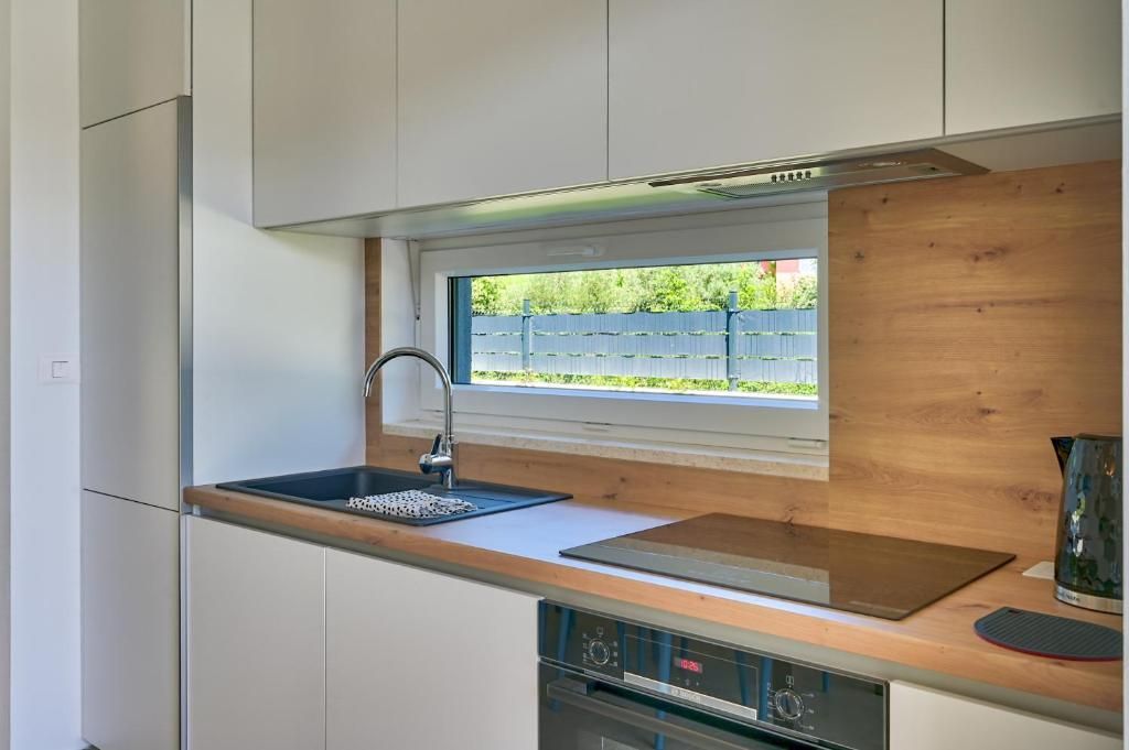 Kuhinja z belimi omaricami, pomivalnim koritom, štedilnikom in oknom.