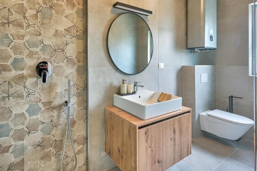 Kopalnica z umivalnikom, straniščem, ogledalom in tušem.