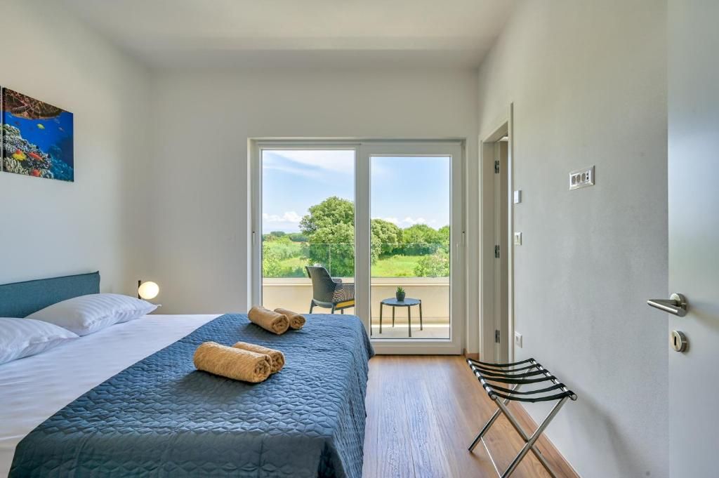 Spalnica z veliko posteljo, drsnimi steklenimi vrati in balkonom.