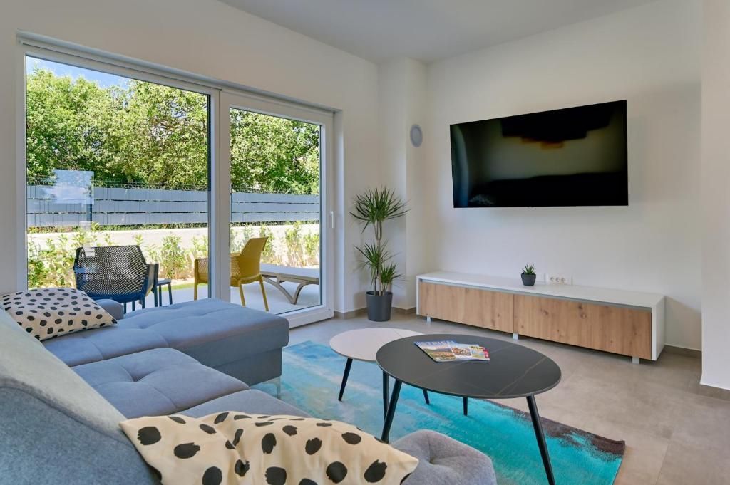 Dnevna soba s kavčem, klubsko mizico, televizijo in drsnimi steklenimi vrati.