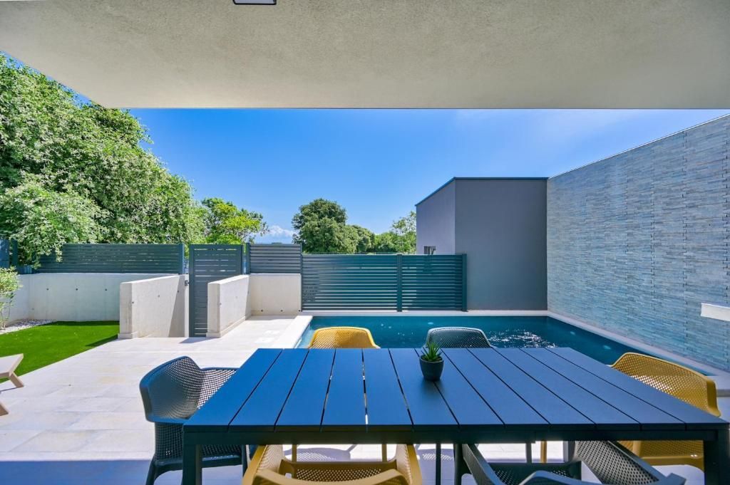 Pred bazenom je miza in stoli.