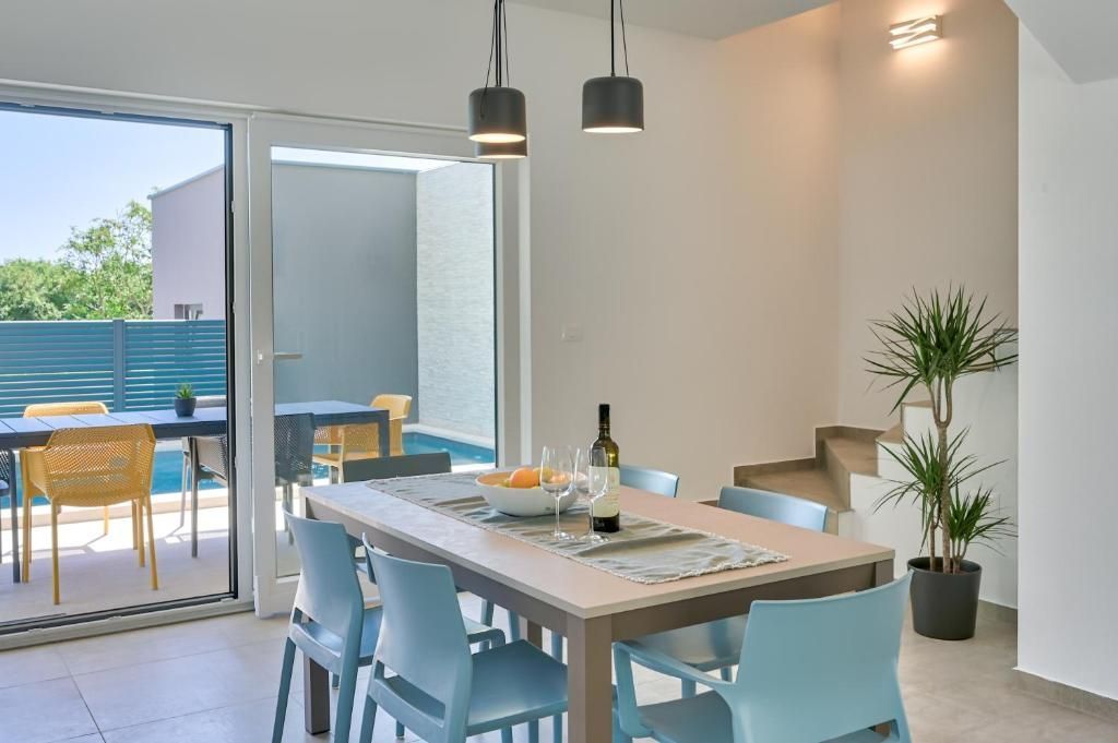 Jedilnica z mizo in stoli ter drsnimi steklenimi vrati, ki vodijo do bazena.