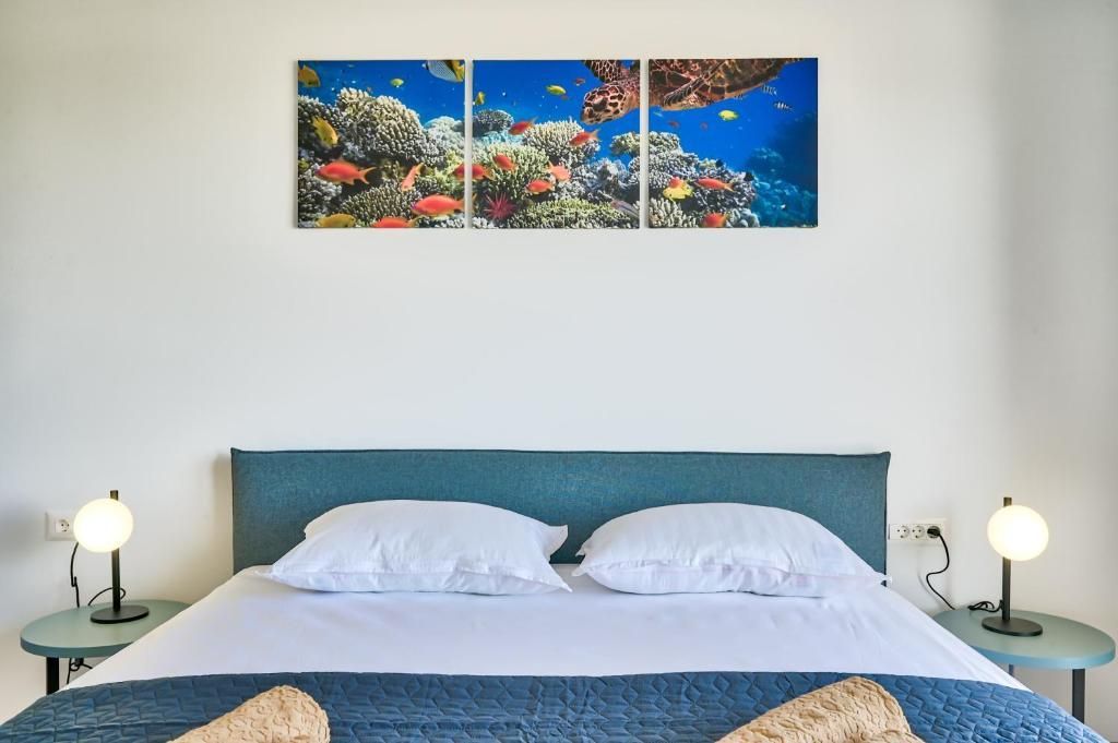 Na steni nad posteljo visi slika koralnega grebena.