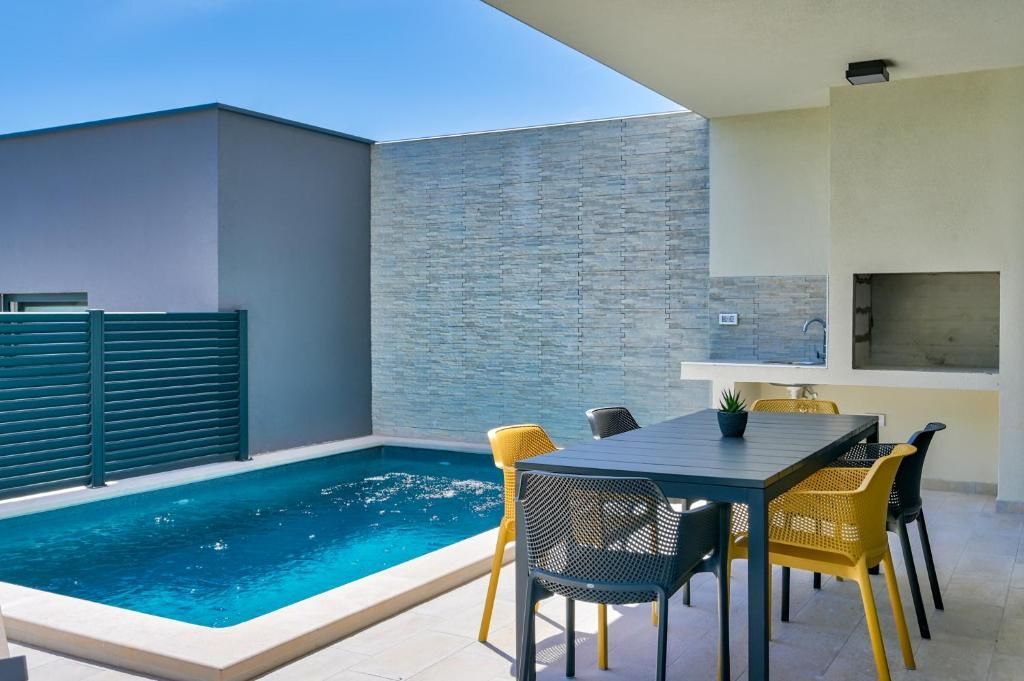 Terasa z mizo in stoli ob bazenu.