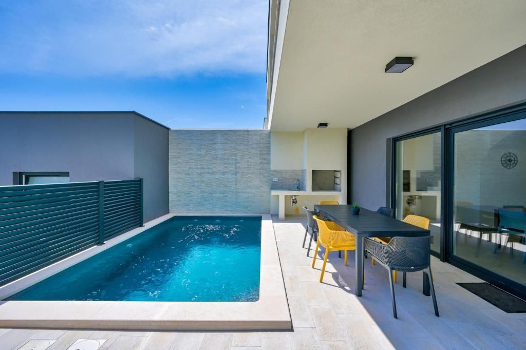 Velik bazen je obdan s teraso z mizo in stoli.