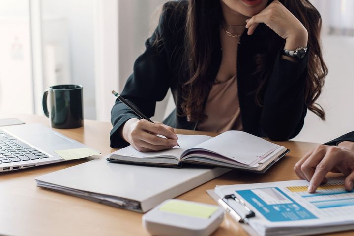 a man and a woman are sitting at a table with papers and a laptop .