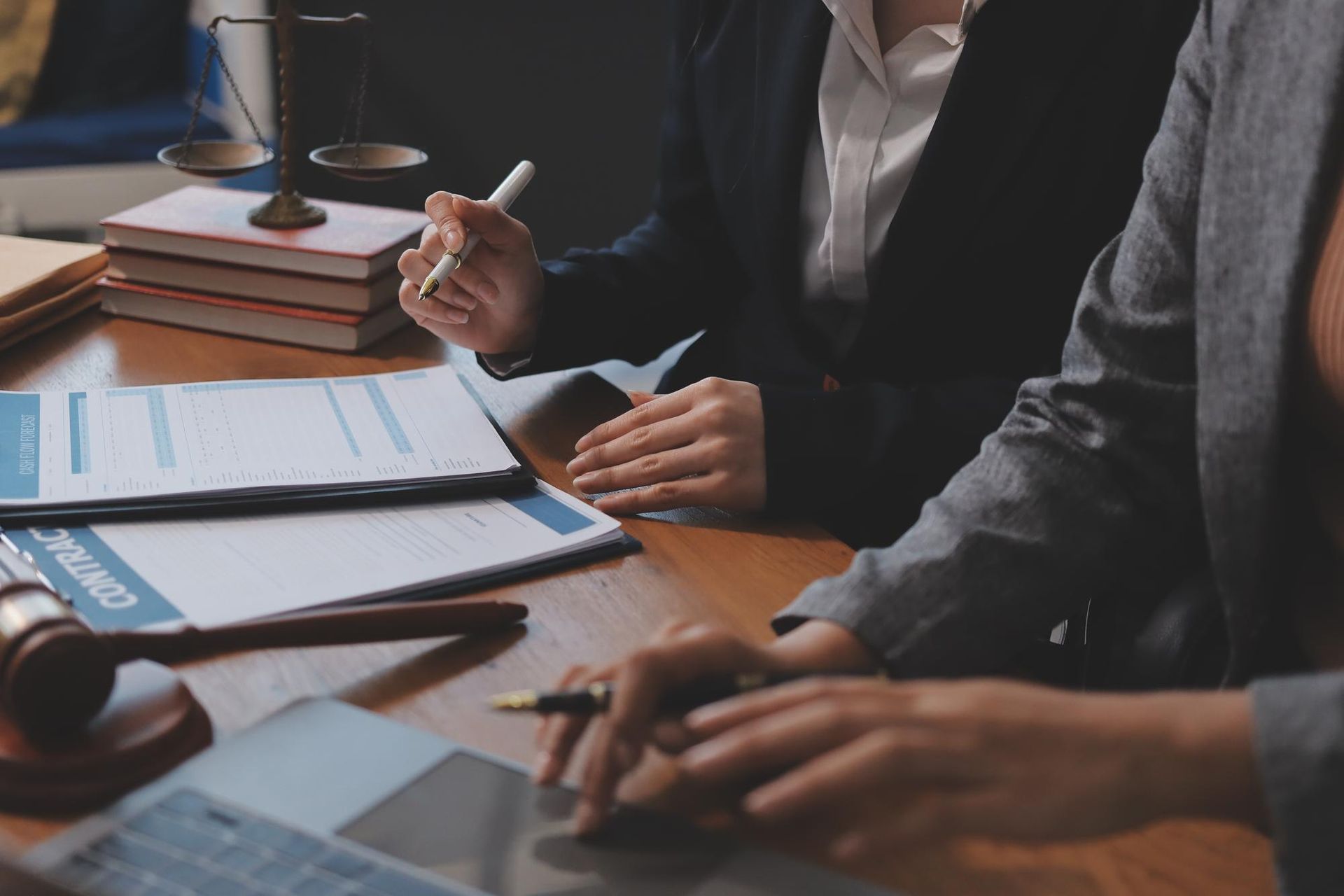 Two people shaking hands over a contract on a desk.