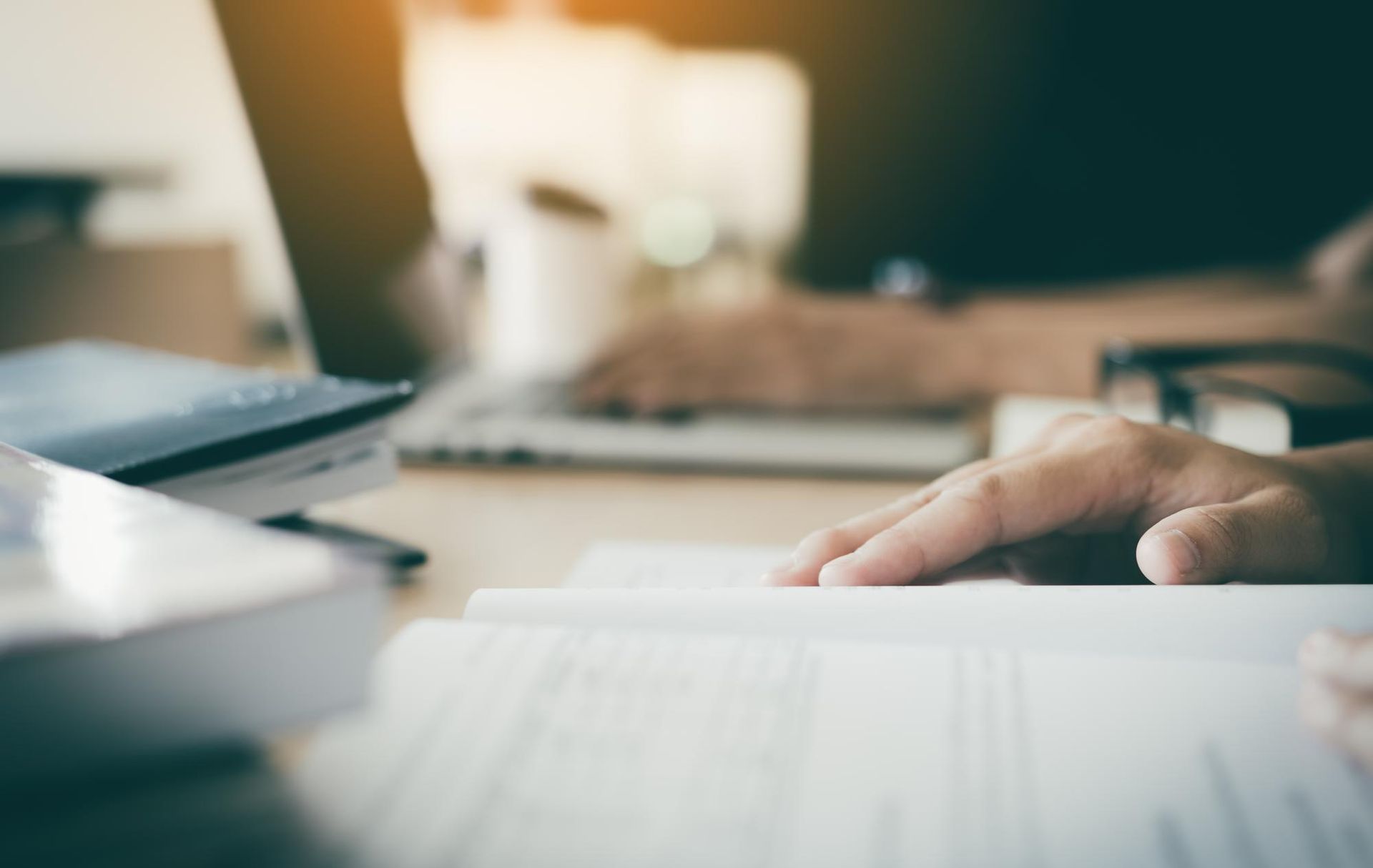 Two people shaking hands over a contract on a desk.
