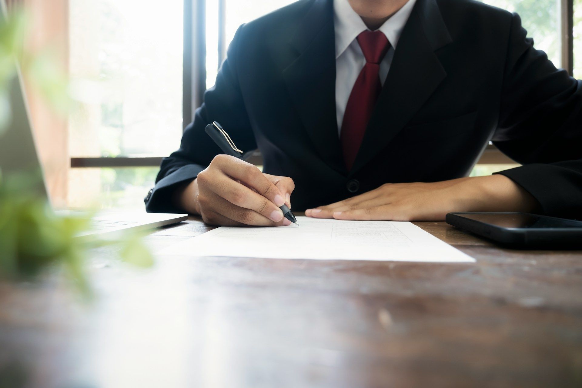 Two people shaking hands over a contract on a desk.