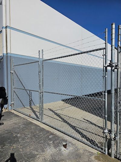 A chain link fence with a gate in front of a building.