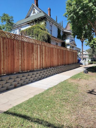 A wooden fence along a sidewalk in front of a house.