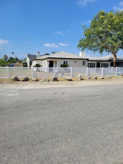 A white house with a white fence and a tree in front of it.