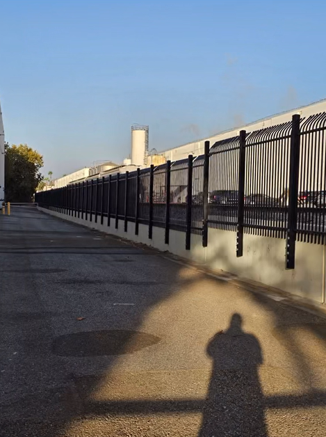 A white fence is sitting on top of a dirt path next to a house.