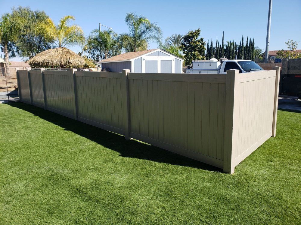 A tan fence is sitting on top of a lush green lawn.