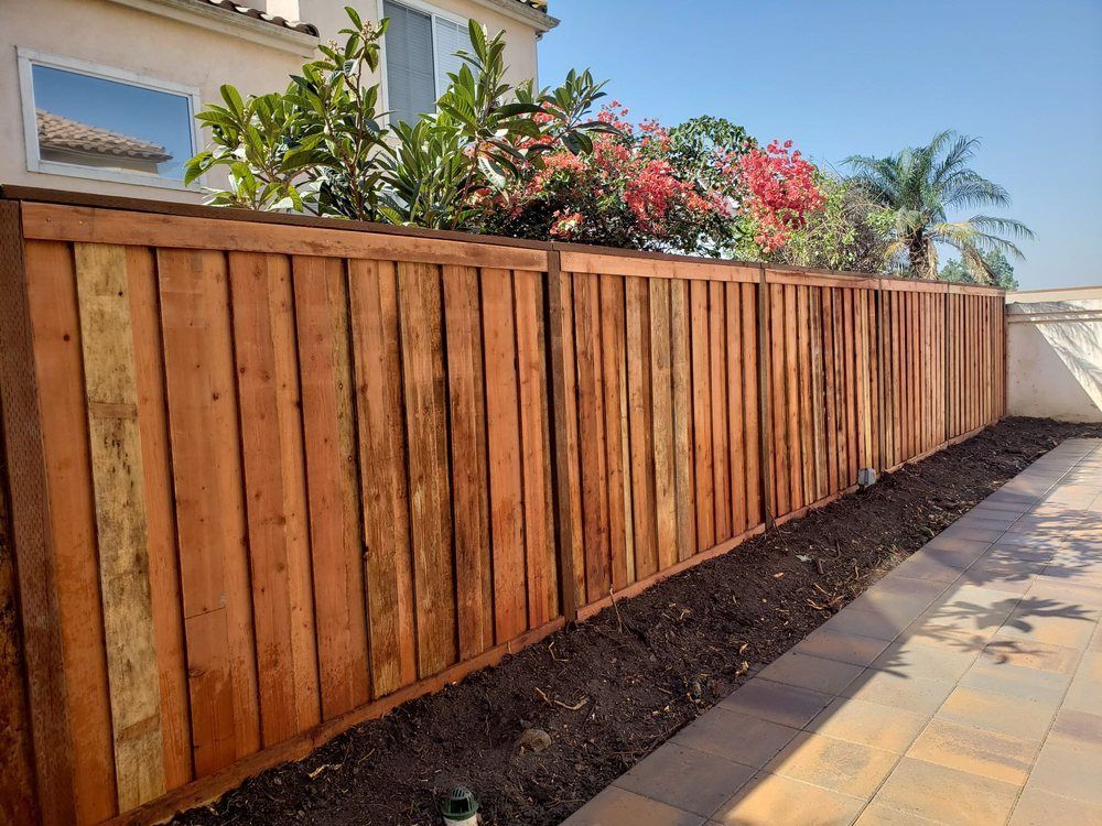 A wooden fence surrounds a patio in front of a house.