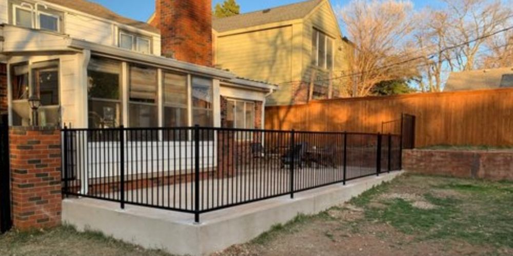A house with a screened in porch and a fence around it.