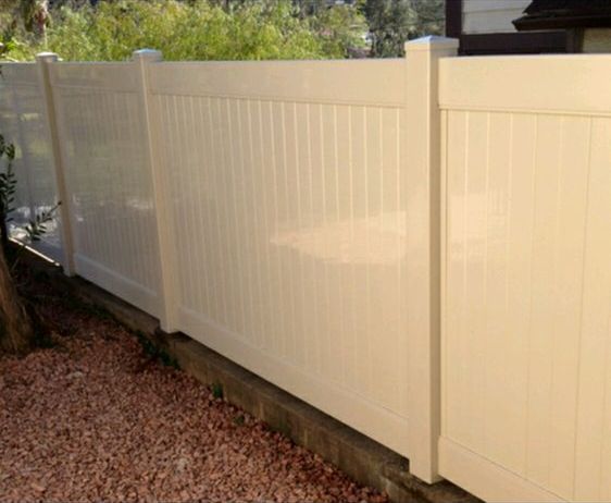 A white vinyl fence is sitting next to a pile of gravel.
