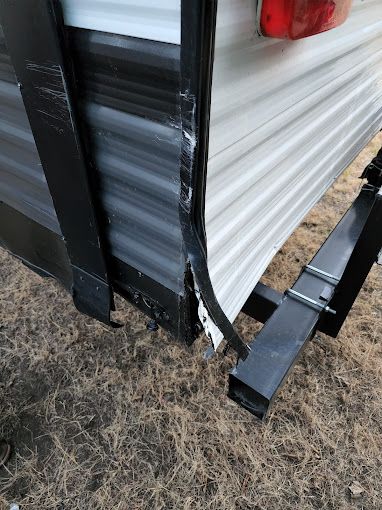 A trailer with a broken door is sitting on the ground.