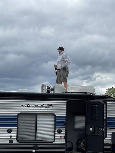 A man is standing on the roof of a rv.