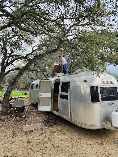 A man is standing on top of an airstream trailer.