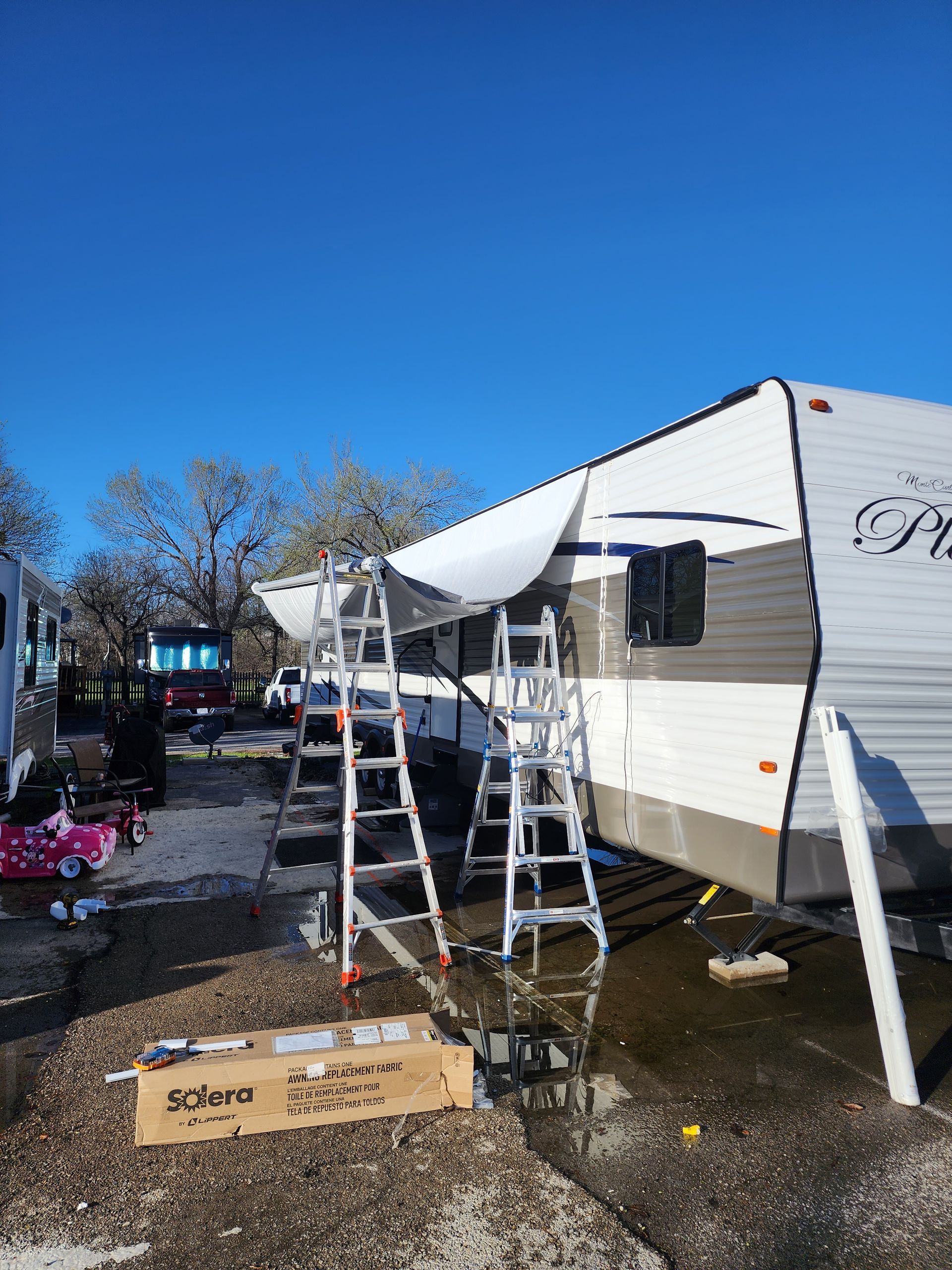 A ladder is sitting next to a trailer in a parking lot.