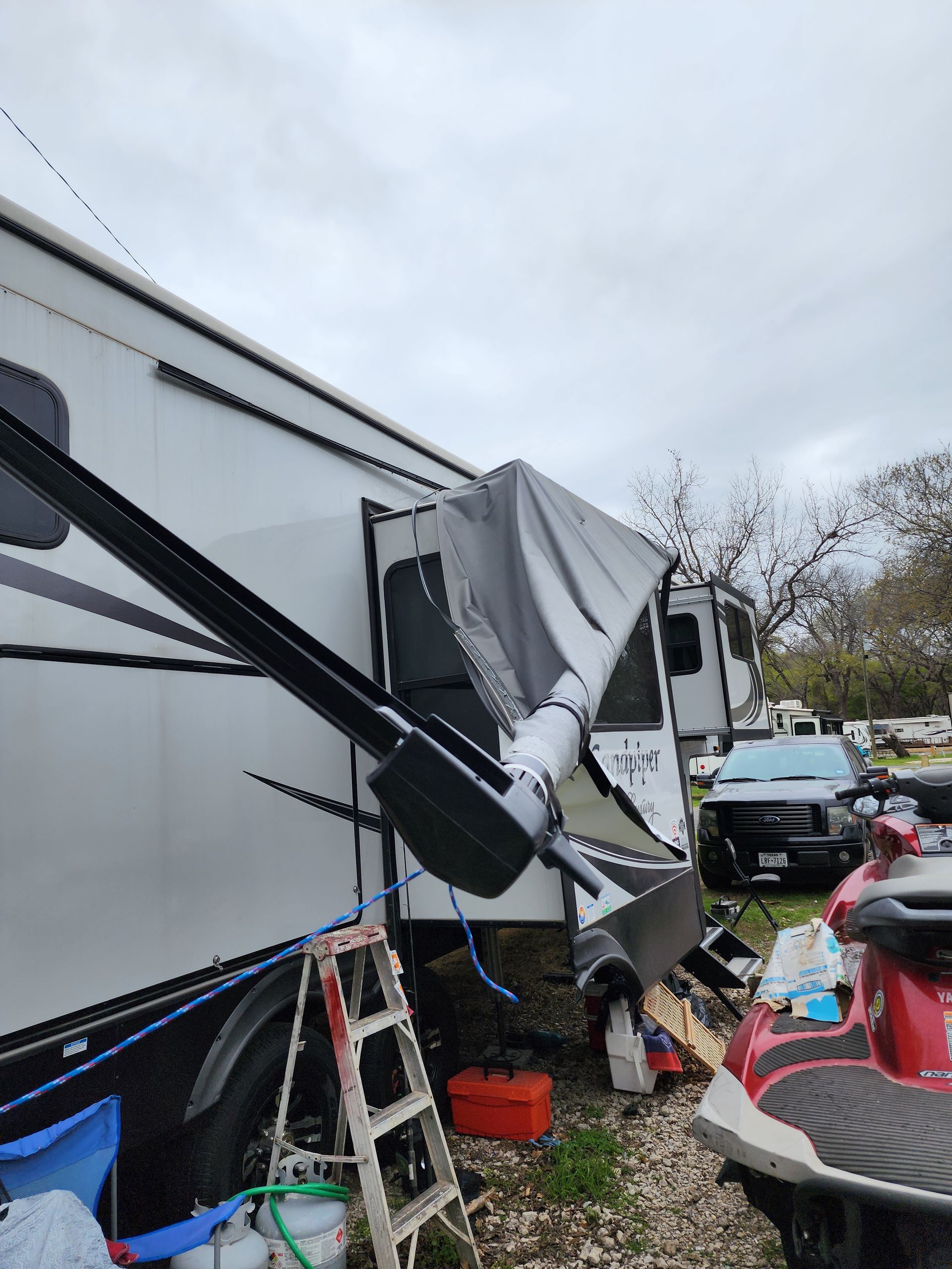 A red jet ski is parked next to a rv.