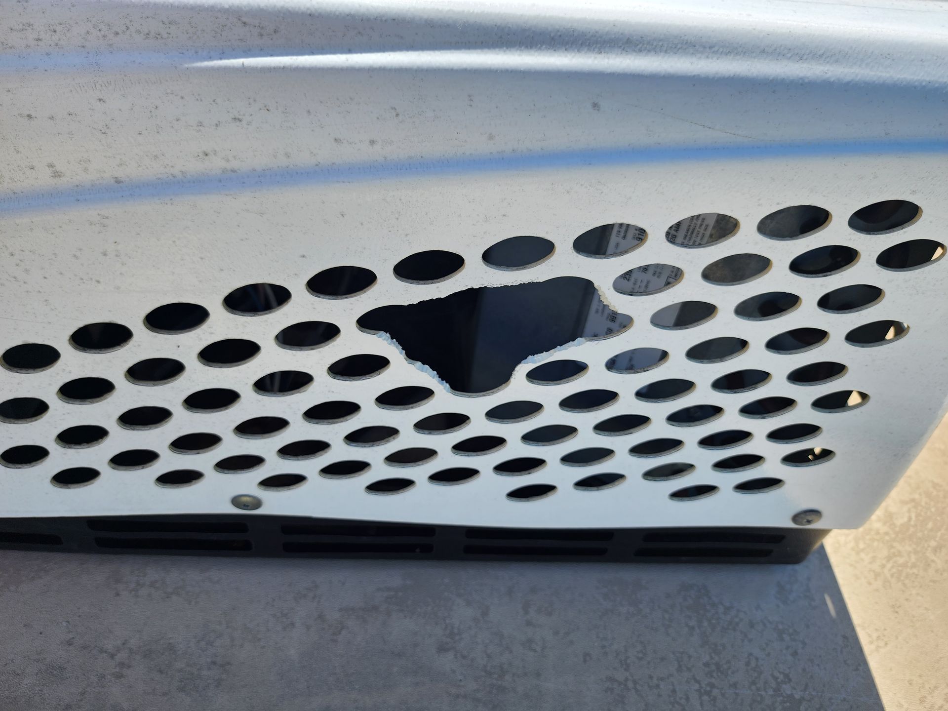 A white crate with holes in it is sitting on the ground