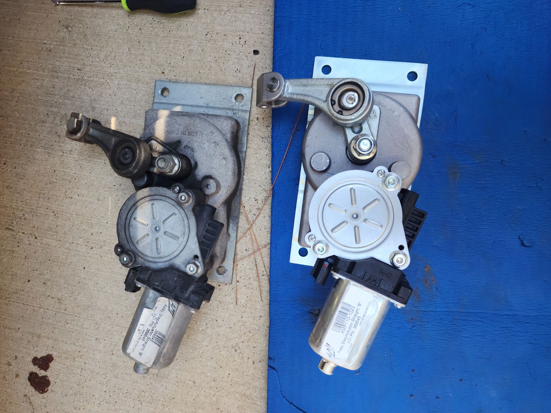 Two motors are sitting next to each other on a blue surface.