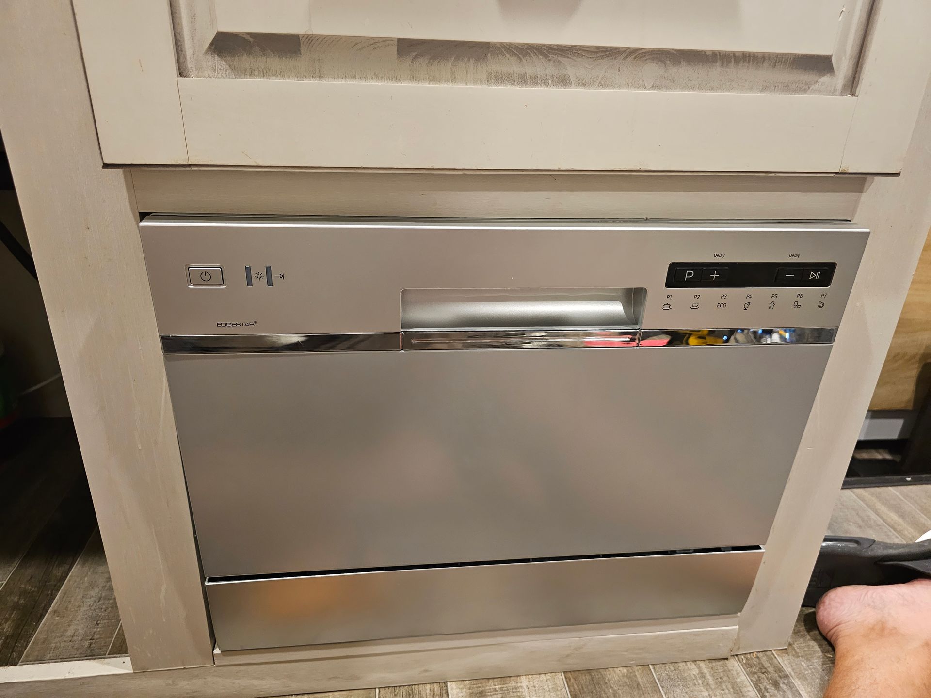 A stainless steel dishwasher is built into a cabinet in a kitchen.