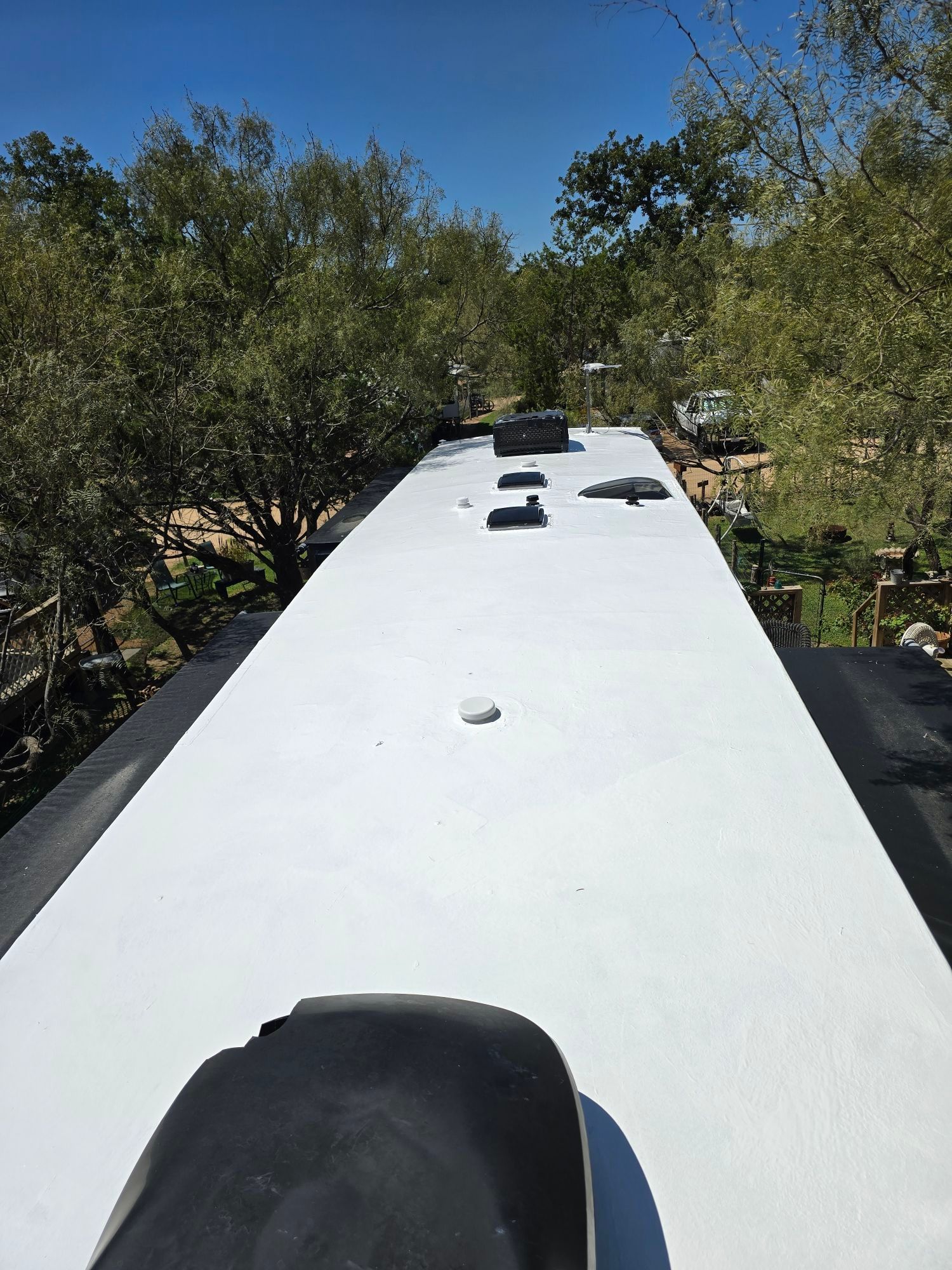 A white roof with a lot of trees in the background.