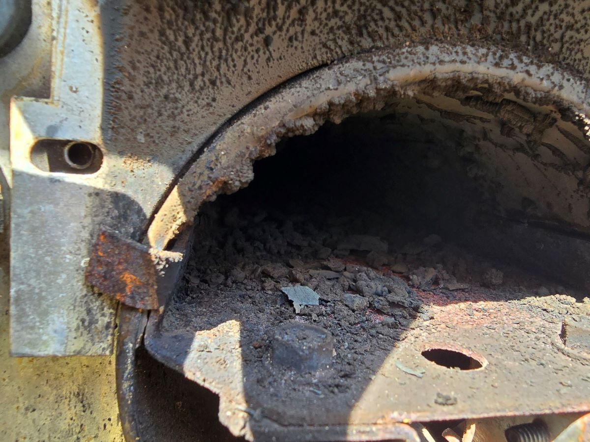 A close up of a rusty metal object with a hole in it