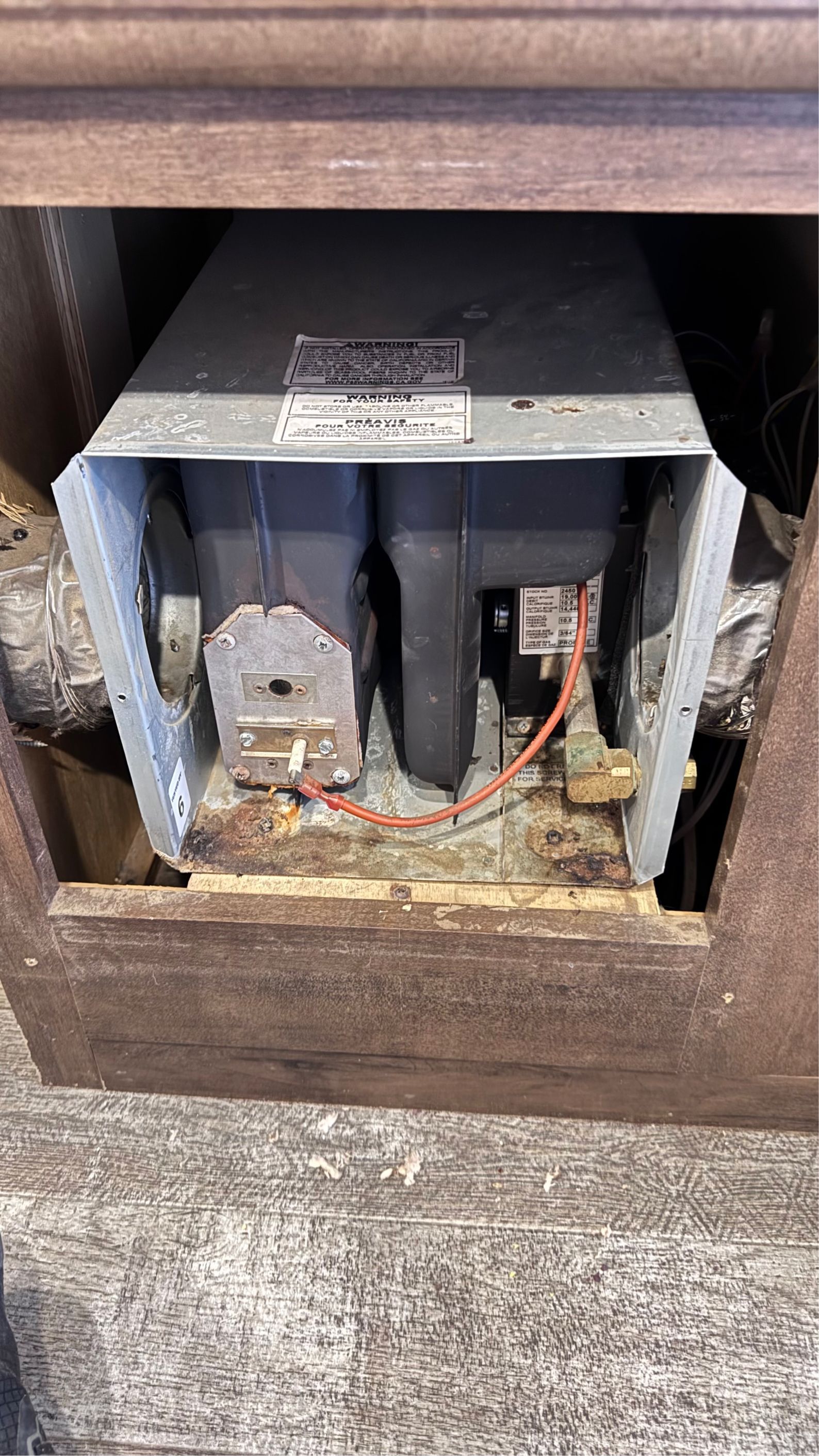 A heater is sitting inside of a wooden cabinet.