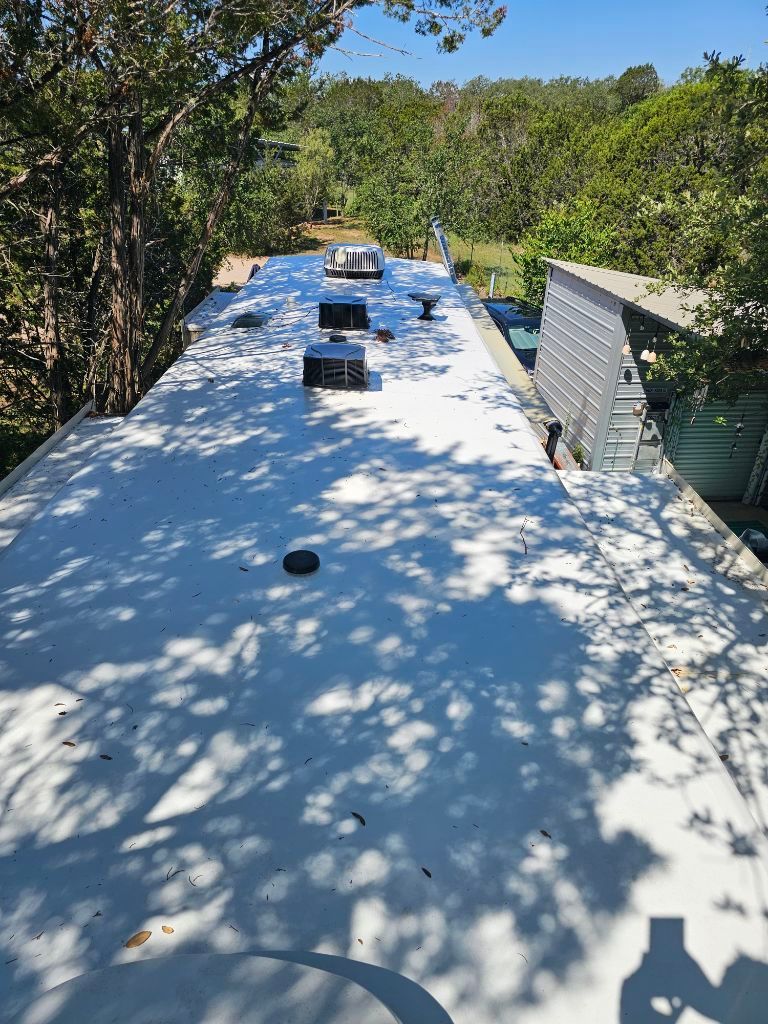 A white roof with a lot of trees in the background.